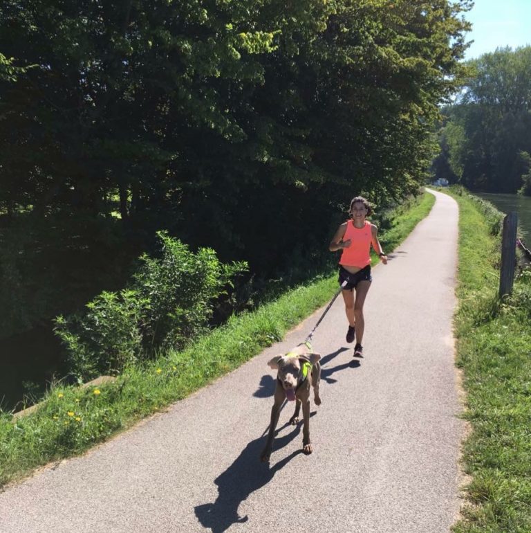 Løper med hund i elastisk trekkline på en sti